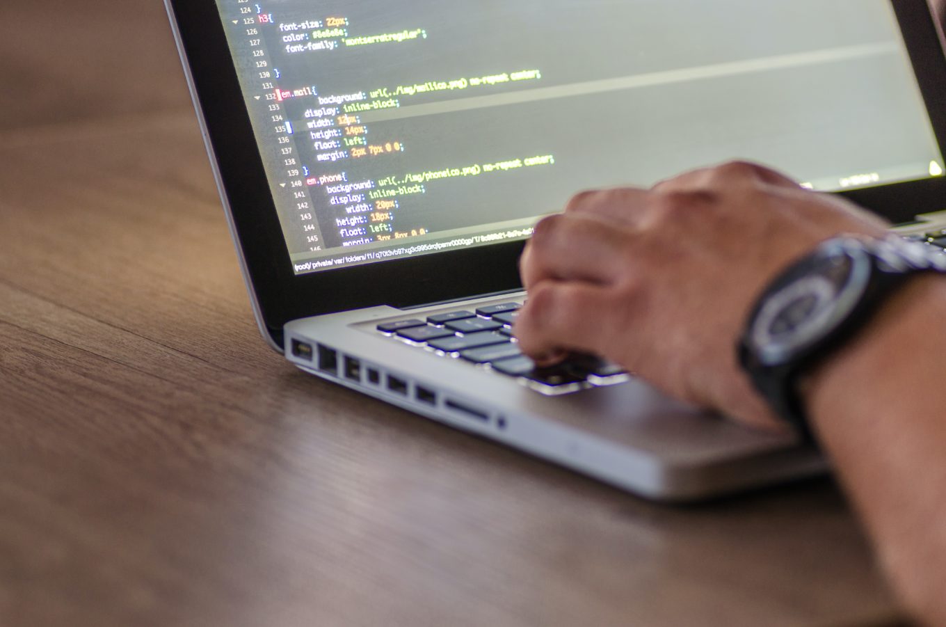 image of a man testing software on a laptop on a pale wood table